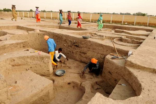 People work during an excavation at a pre-Harappan site, at Kunal village.