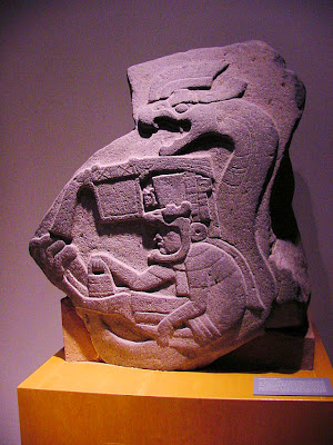 A priest / god, wearing a large headdress, sits on the belly of a great rattlesnake in this monumental carving (c. 800 BC). From La Venta Stela 19. Source: Wikipedia